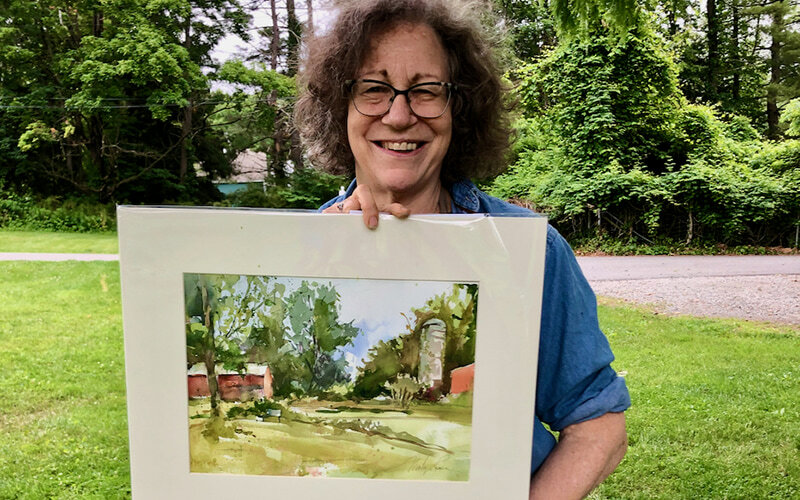 Artist Marilyn Rose holds up a watercolor