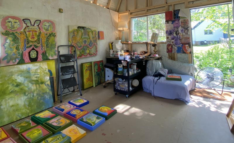 Shelby Little’s art studio filled with vibrant, myth-inspired paintings, stacked canvases, and a rolling cart of paints and brushes. The space features large windows letting in natural light, a cozy striped couch, and artwork in progress scattered across the floor. With help from Artwork Archive, Little keeps her creative space organized while surrounded by the color, movement, and layered narratives that define her practice. Photo courtesy of the artist.