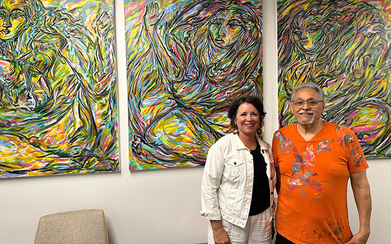 Artist in front of his paintings