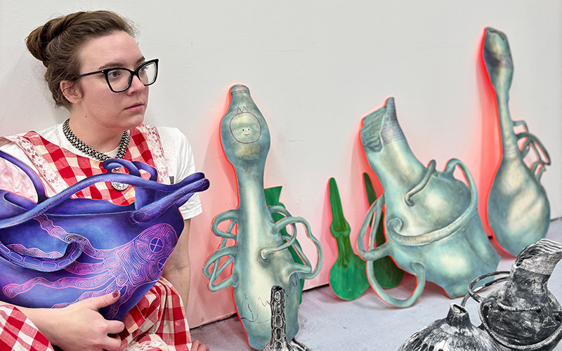 An artist holding her painting in her studio