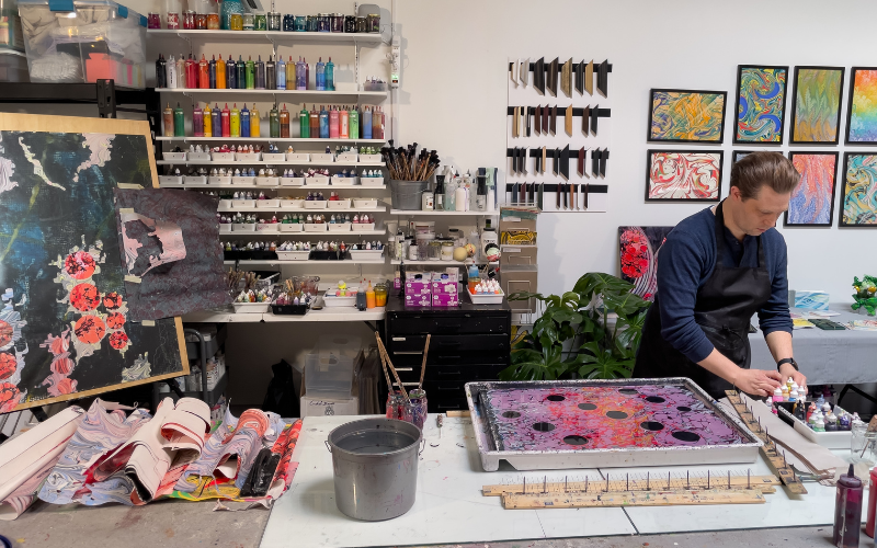 Keith Garubba prepares his marbling tray in his studio, with finished works lining the walls and rolled sheets from the day's practice piled nearby. Photo courtesy of the artist.