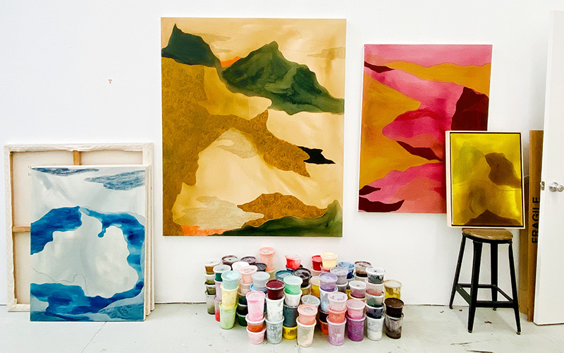 Photo of muted-palette abstract paintings in a white-walled studio