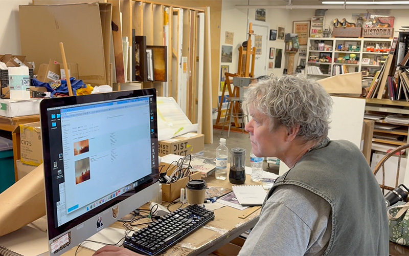 An artist working at his computer in his studio