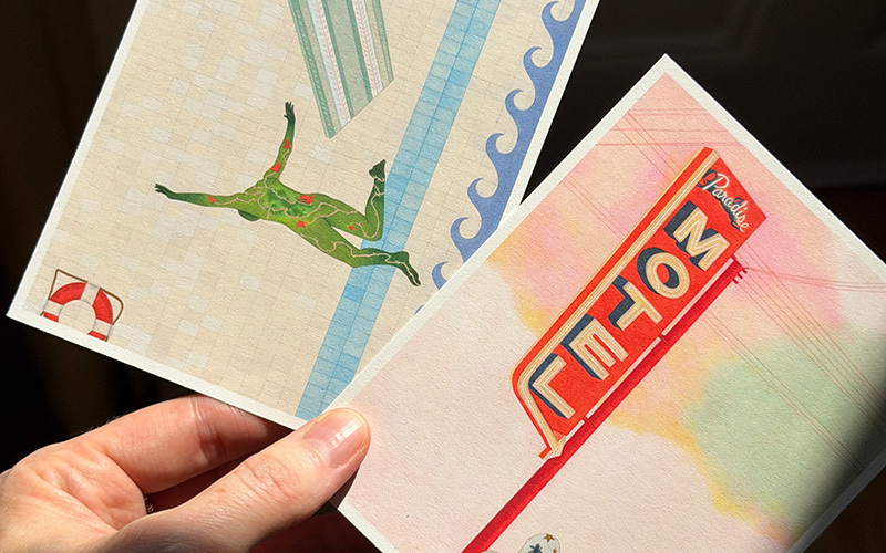 A hand holding two small artist prints