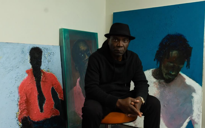 Several of Temi Wynston Edun's figurative paintings surround the artist as he sits in his studio