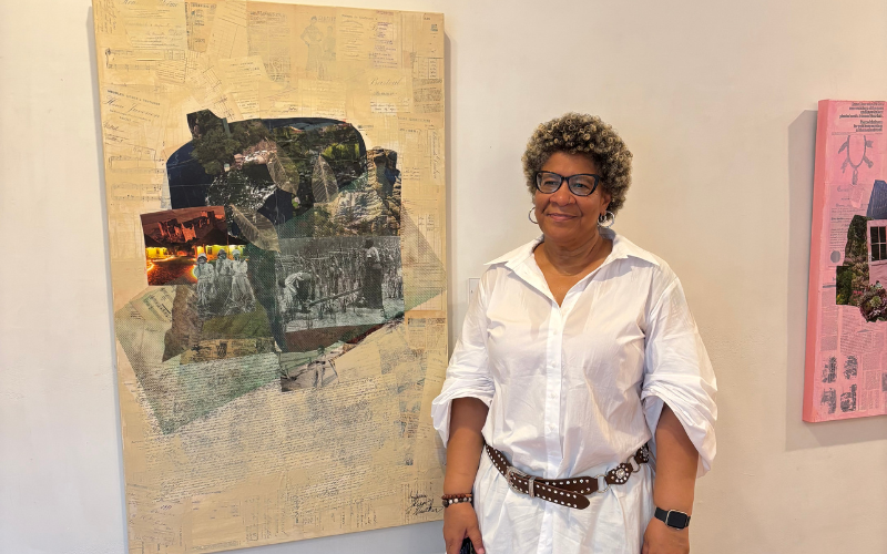 Collage artist Indigene Theresa Gaskin stands beside one of her large document-layered collages at an exhibition, with a second pink-toned work visible nearby.